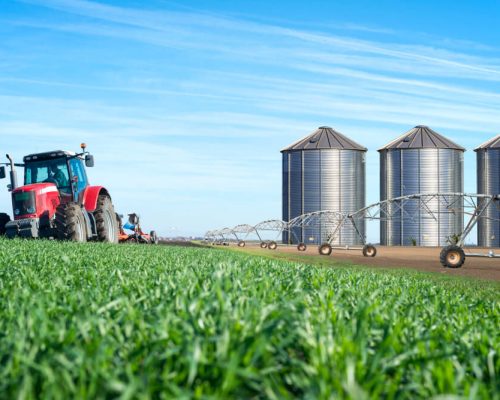 agricultura-e-conceito-de-producao-de-alimentos-com-silos-de-maquina-de-trator-e-sistema-de-irrigacao (1)